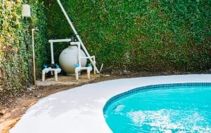 Pool pump and sand filter system installed beside a swimming pool.